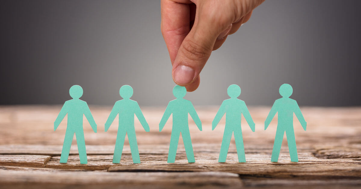 Eine Hand greift eine Figur aus einer Papierkette.