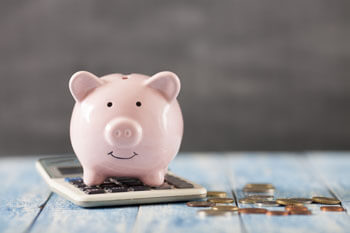 Sparschwein mit Taschenrechner und Münzen.