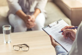 Ein Sozialpsychologe spricht mit einer Patientin und macht sich Notizen.