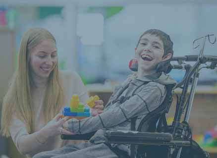 Sonderpädagogin spricht mit einem Jungen im Rollstuhl